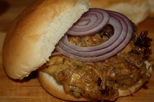 Smoky Brisket and Cheese Mixture In a White Bread Bun, Topped With a Slice of Red Onion Smoked Brisket Combined With Melted Cheese Makes a Great Tasting Sandwich