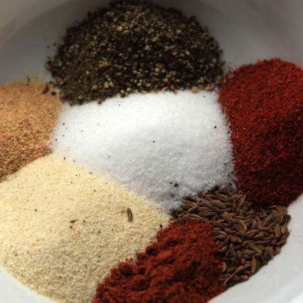 Dry Rub For Chicken, Ingredients In Bowl Before Mixing Include Salt, Onion Powder, Black Pepper and Caraway Seeds