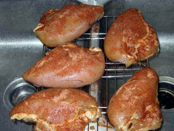 Chicken Breasts Seasoned With Dry Rub, Resting On a Wire Grate Over The Kitchen Sink