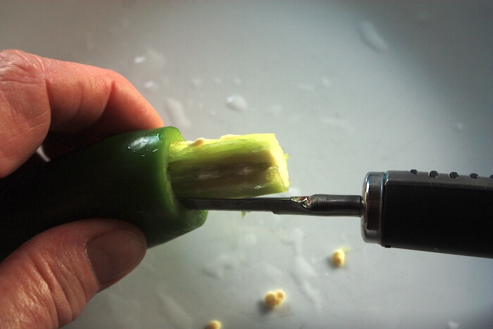 Pulling the seedy core out of a jalapeno pepper.