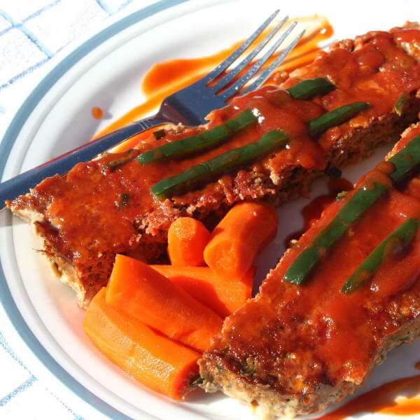 Meatloaf On Plate With a Fork, Topped With Poblano Pepper Sauce and Pepper Slices