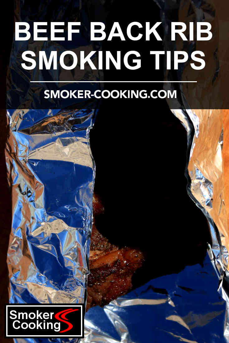 A rack of beef back ribs, partially cooked in a smoker, being wrapped in foil for the final cooking period. Pin for later