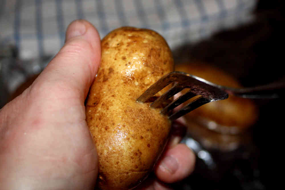 Poking holes into a whole potato in preparation for the brining step of this smoked potato making process.