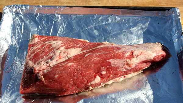 A Single, Raw Beef Tri Tip Roast On Aluminum Foil