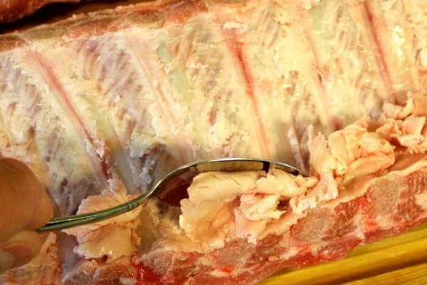 Use a Spoon To Remove Fat From The Bone Side of Pork Ribs - It Fits Perfectly Between The Rib Bones Scraping Fat From a Slab of Pork Ribs