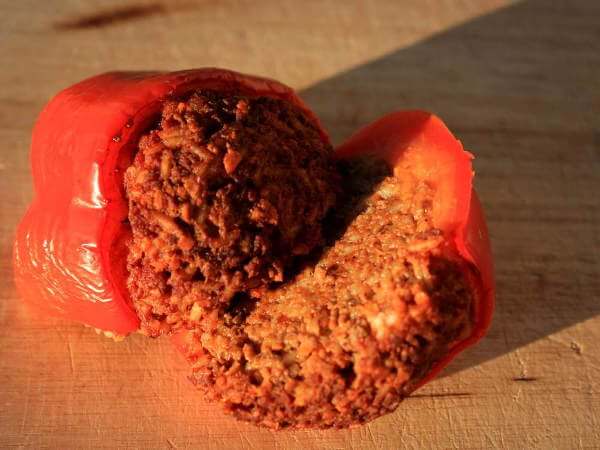 Stuffed and Smoked Red Bell Pepper Sliced Into Half, Resting On a Small Bamboo Cutting Board Closeup Picture Of a Smokey Stuffed Red Bell Pepper, Cut Into Half To Display The Moist, Flavorful Filling