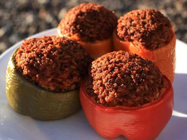 Stuffed Yellow, Green, Orange and Red Sweet Bell Peppers On Plate, Just Removed From The Smoker Four Sweet Bell Peppers, Red, Yellow, Orange and Green, Filled With Seasoned Ground Beef Mixture And Cooked In The Smoker