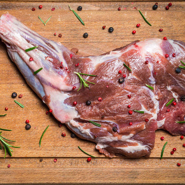 Uncooked Venison Leg With Peppercorns and Rosemary Raw Leg of Venison On Wooden Surface, Preparing to De-Bone and Stuff With Sausage