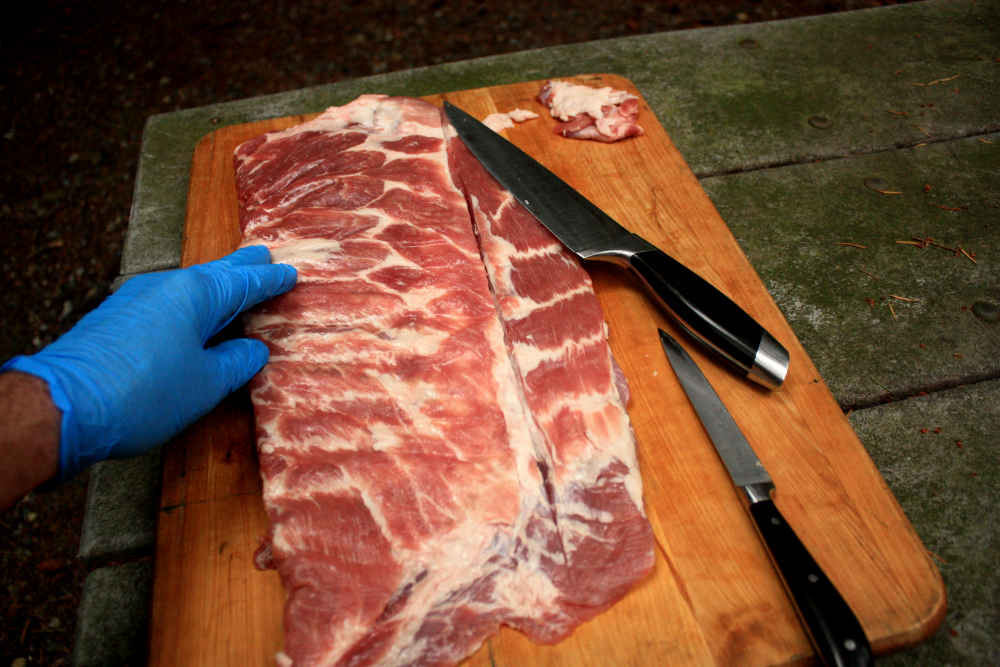 Trimming a sparerib slab. A cut line scored into the meat shows where the fat line is that marks the position of the cut made to remove the rib tip section.