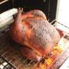 A whole chicken, finished cooking in the smoker, browned nicely and ready to eat